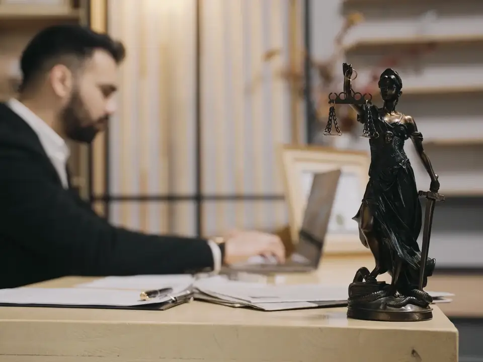 Abogado trabajando en su despacho junto a una figura de la Justicia